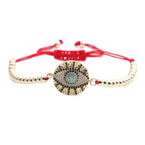Macro detail of Evil Eye charm bracelet with blue zircon and adjustable red braided cord