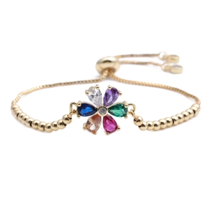Detailed shot of a gold adjustable chain bracelet with a colorful gemstone floral charm
