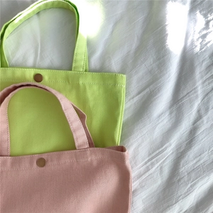 Top view of pastel pink and green corduroy tote bags with vintage metal magnetic snap buttons