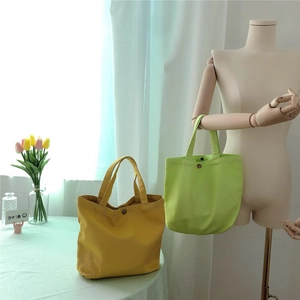 Close-up of vibrant yellow and lime green canvas tote bags with metal snap button closure