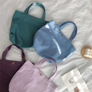 Detail of four Morandi canvas handbags in deep green and purple with metal snaps