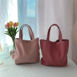 Detail of corduroy tote bags with snap buttons and vertical texture in pastel pink tones