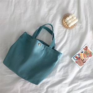 Detail of blue corduroy tote bag with metal snap button on white fabric background