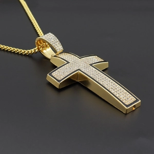 Macro shot of gold cross pendant with clear rhinestones and black enamel detail