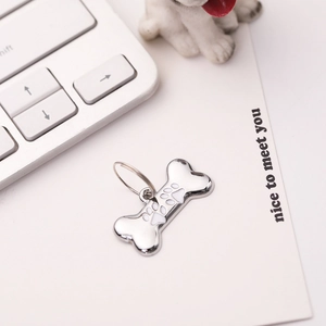 Detailed view of a silver bone-shaped pet tag with white paw print and metal ring attachment