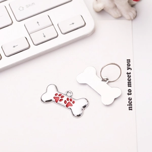 Macro shot of bone-shaped metal dog tags with a red paw print and polished silver finish