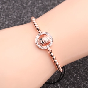 Rose gold beaded bracelet with micro-pave skull charm on a dark glitter background