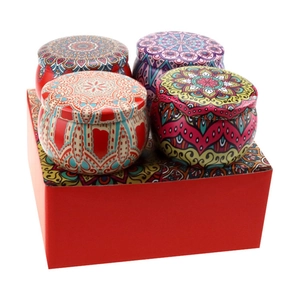 Set of four mandala soy wax candles in decorative tin jars on a red gift box