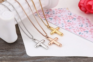Detailed view of polished cross pendant necklaces in gold, silver, and rose gold finishes