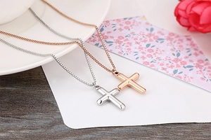 Polished silver and rose gold cross pendants with box chains on white porcelain