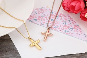Detail of gold and rose gold cross necklaces on white ceramic with roses