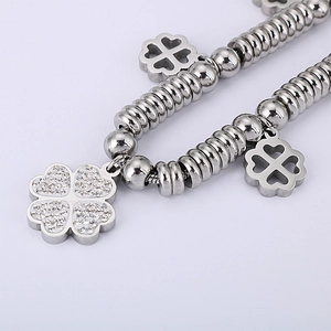 Silver beaded bracelet with clover charms and sparkling white rhinestones on grey background