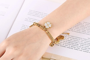 Detail of gold clover bracelet with micro-pave cubic zirconia on a model's wrist