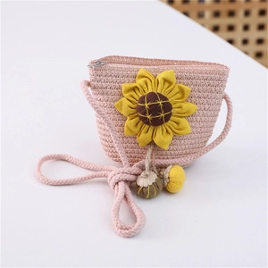 Detailed view of pink straw crossbody bag with yellow sunflower and hanging ball charms