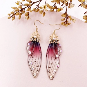 Macro detail of gradient purple cicada wing earrings with crystal accents and gold hooks