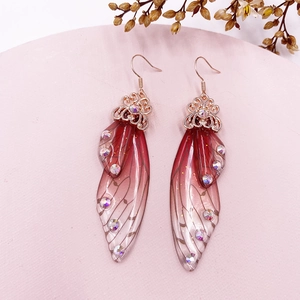 Detailed macro view of S925 silver butterfly wing earrings with red gradient and rhinestones