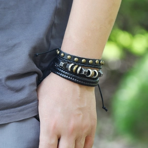 Retro multi-layer black leather bracelet set with bronze studs and metal beads worn outdoors