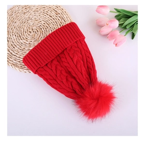 Detail view of the red chunky cable knit beanie with faux fur pom pom and ribbed cuff