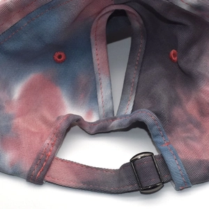 Detail view of tie-dye baseball cap with pony tail hole and adjustable metal buckle