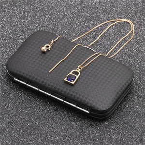 Detail of gold lock pendant with blue square gemstone on black textured surface