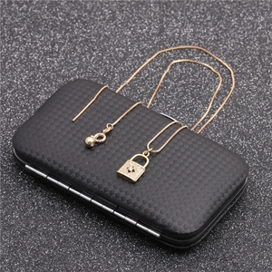 Detail of a golden lock pendant necklace with zircon stones on a black textured box