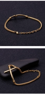 Close-up of golden stainless steel chain bracelet featuring a cross charm and lobster clasp