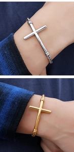 Detail showing gold and silver stainless steel cross bracelets on a wrist with chain links