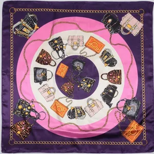 Detailed close-up of a square silk scarf featuring luxury bag illustrations and gold chains