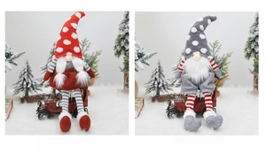 Close-up of sitting Christmas gnomes with knit hats and striped legs on snowy background