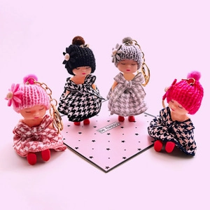 Close-up of cute doll keychains with knitted hats and houndstooth skirts in four colors