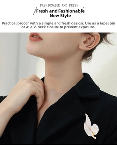 Detail of white leaf brooch with gold edges and pearls on a black suit lapel