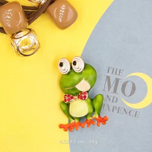 Detailed close-up of a green frog brooch with a red rhinestone bow on a colorful background