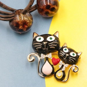 Elegant black cat brooch with diamonds and red heart set against a bicolor background