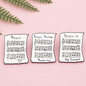 Broches en émail en forme de parchemin musical avec des notes sur un fond rose pastel