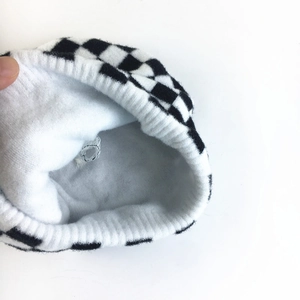 Macro shot of knitted beanie showing black and white checkerboard pattern and plush lining