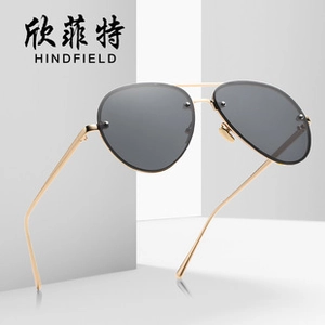 Detail shot of rimless aviator sunglasses with gold metal frame and dark grey lenses