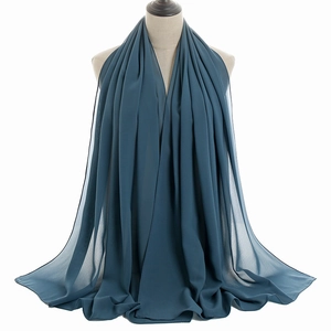 Detail of dark teal chiffon scarf with textured pleats and smooth hem on a mannequin