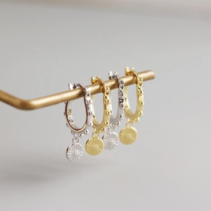 Gros plan de boucles d'oreilles créoles S925 en argent avec breloques soleil rayonnant