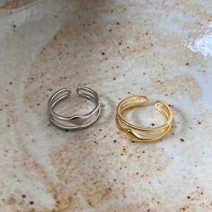 Close-up of minimalist double-layered open rings in gold and silver finish on ceramic tray
