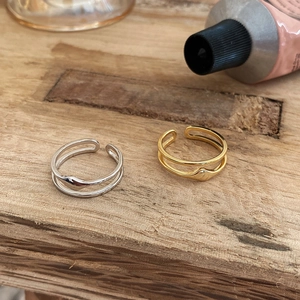 Detail shot of double-layer silver and gold adjustable rings on a wooden surface