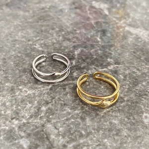 Detail of minimalist double-layered silver and gold rings on a grey stone texture base