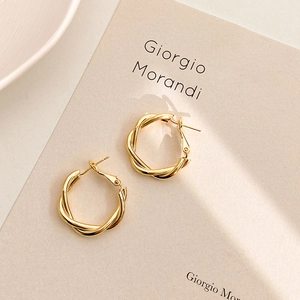 Minimalist gold geometric twisted hoop earrings with a polished metallic finish