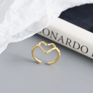 Close-up of golden geometric heart ring with unique foil texture finish on book
