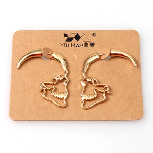 Gothic style gold skull and bull horn silhouette stud earrings on kraft display card
