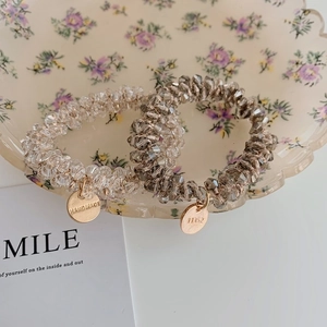 Detail view of handmade faceted crystal bead elastic bracelets with engraved metal tags