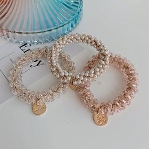 Detailed shot of three hair ties with pearls and pink crystals on a white background