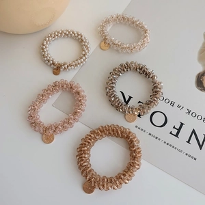 Detailed close-up of 5-piece pearl elastic hair ties with gold handmade metal charms