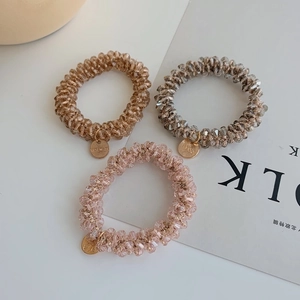 Close-up of handmade crystal beaded hair ties in champagne, grey, and soft pink shades