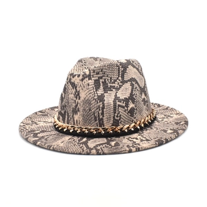Dettaglio del cappello fedora con motivo a serpente e catena a maglie dorate spesse