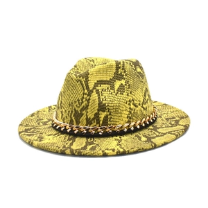 Dettaglio del cappello fedora giallo pitonato con una vistosa catena dorata decorativa